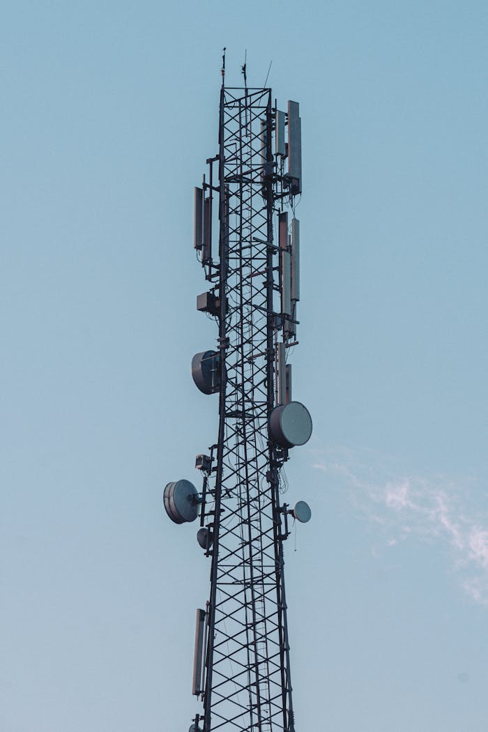 Low angle shot of a steel antenna tower against a clear blue sky, showcasing modern communication technology.
