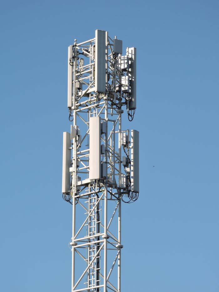 Close-up of a communication tower with antennas against a clear blue sky, emphasizing modern technology.